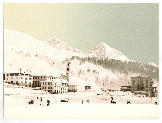 Winter scene with buildings, snow covered peaks in the background